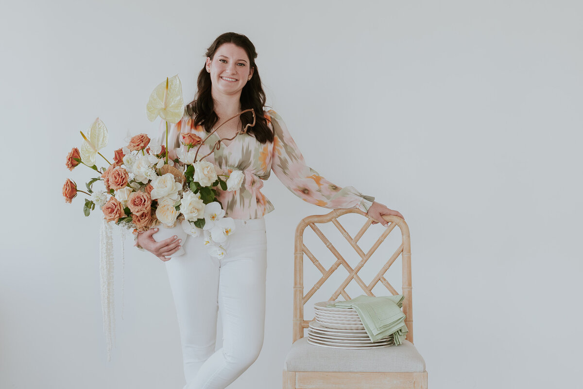 landscape-orientation-photo-event-planner-holding-floral-arrangement-next-to-chair-for-brand-photo-the-frame-charlotte