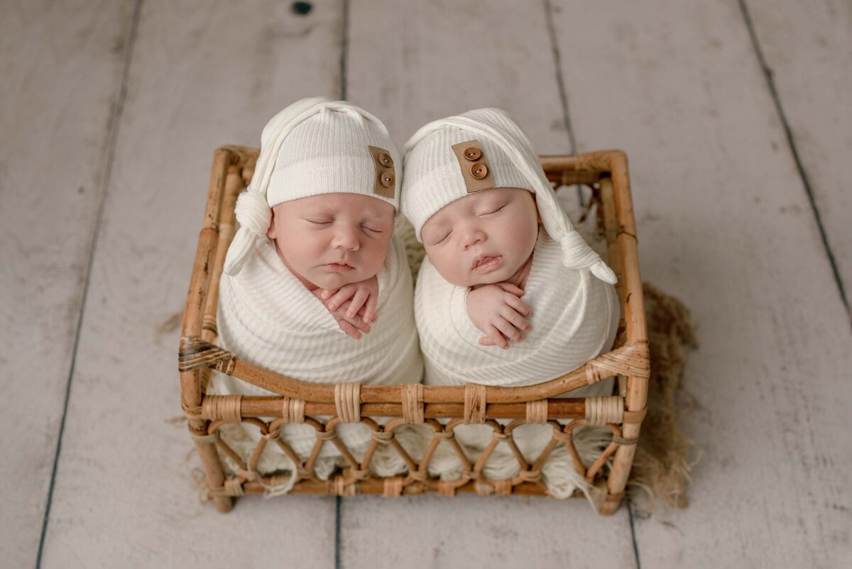 Pensacola FL Newborn Photographer twin baby studio session with twins swaddled in cream wearing sleepy hats placed in bed prop