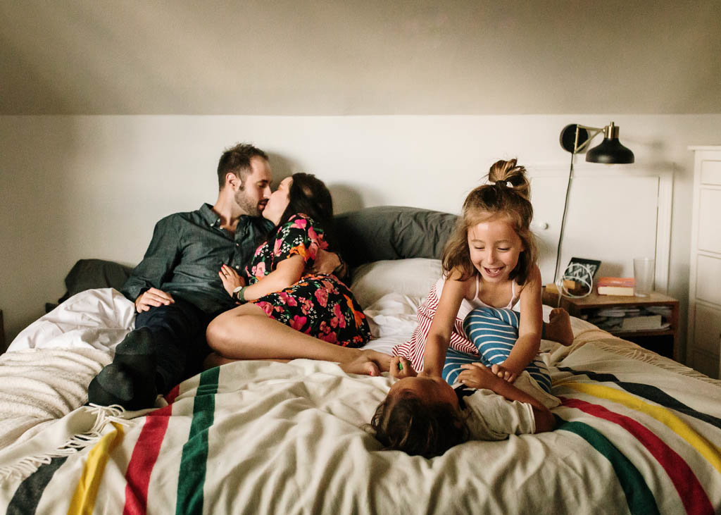 San Francisco in home lifestyle family photography session parents kssing on bed and children wrestling