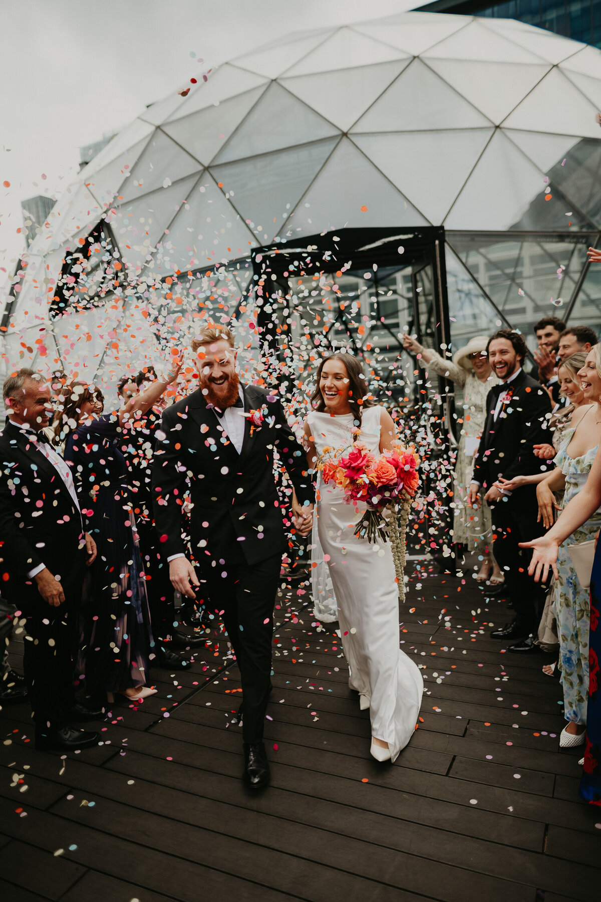 Wedding guests throw confetti at a bride and groom at The Dome at ABC Buildings in Manchester. 
