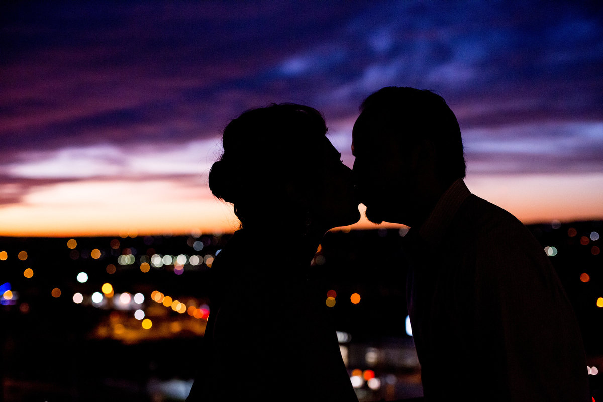 Silhouette of bride and groom kissing in front of colorful sunset right after wedding ceremony plaza lecea