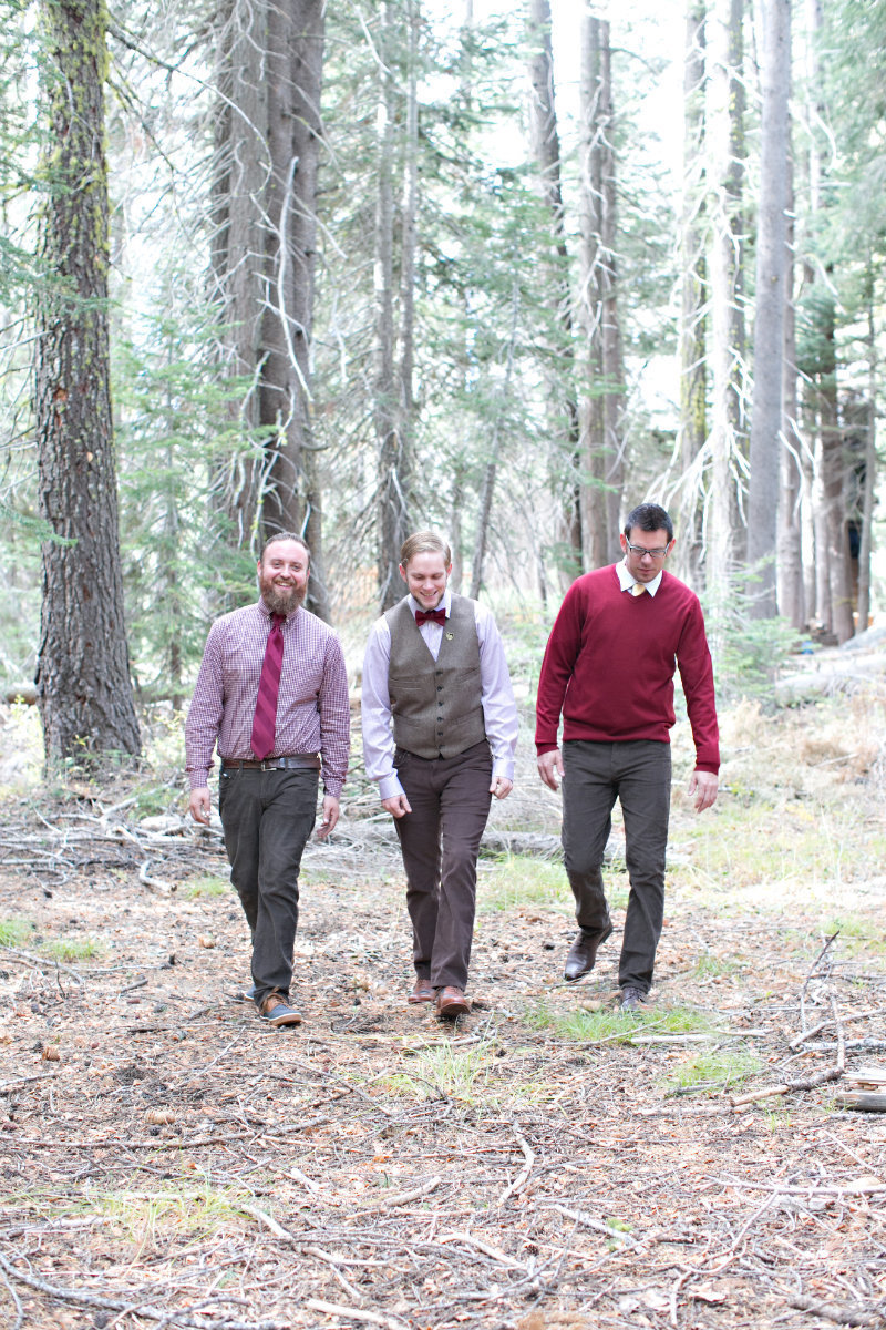 Groom and groomsmens wearing shades of read walking in Tahoe forest