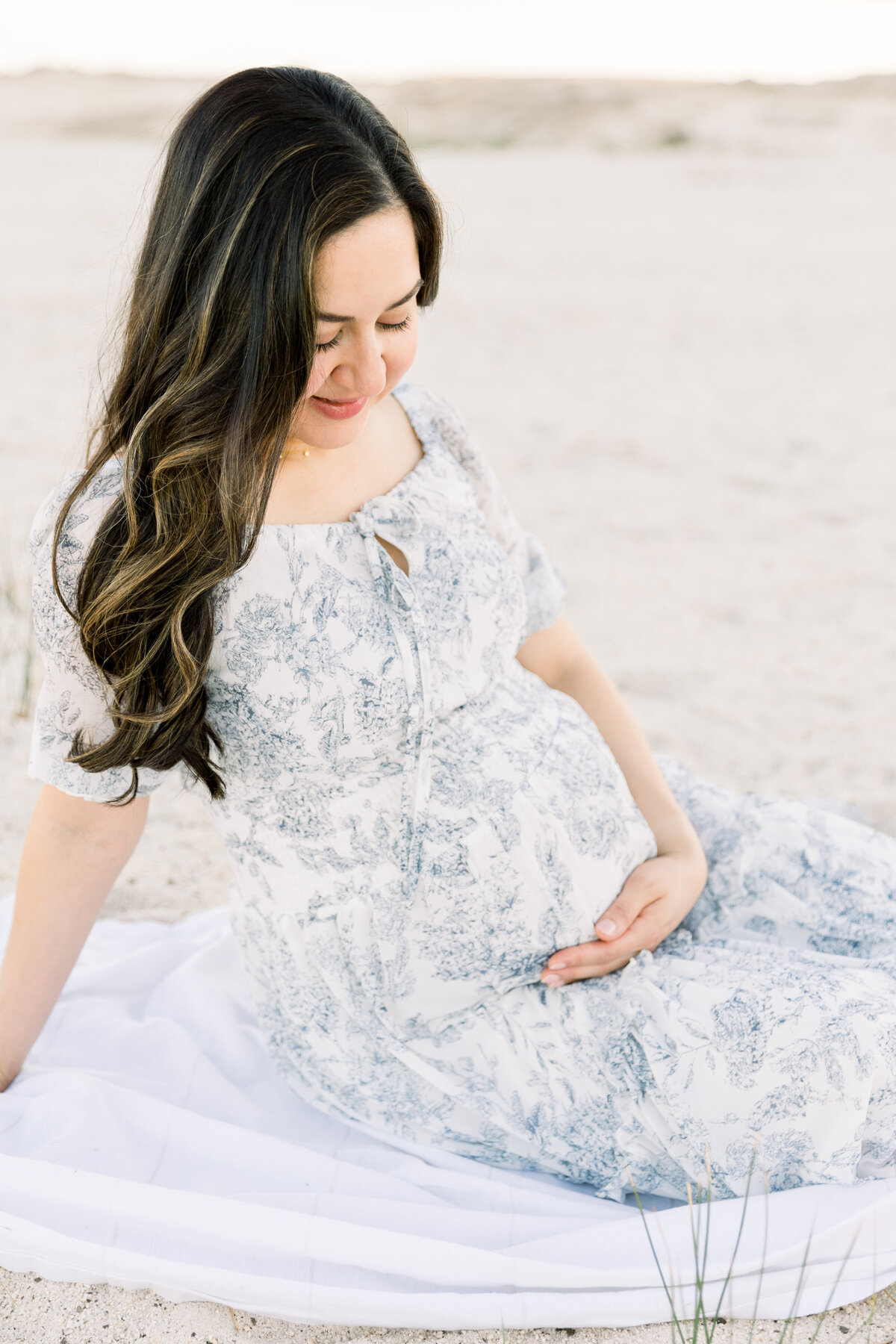 Expecting mother sitting and holding her baby bump taken by Sacramento Maternity Photographer Kelsey Krall
