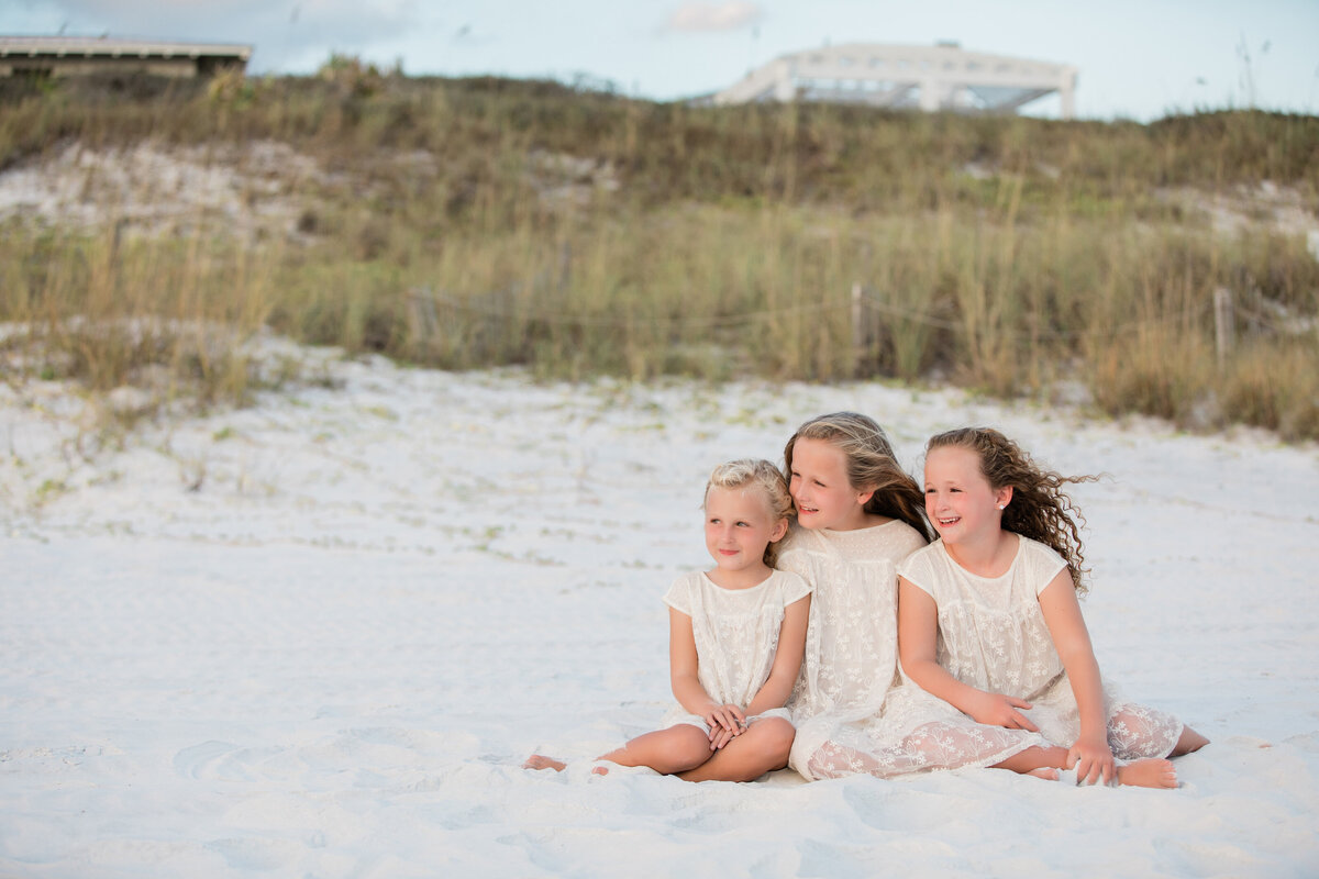 Three kids sitting on the beach together