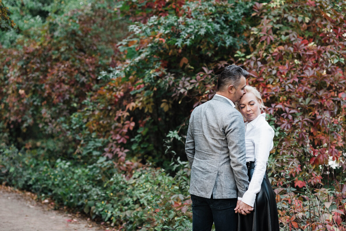 Couple standing in front of fall leaves