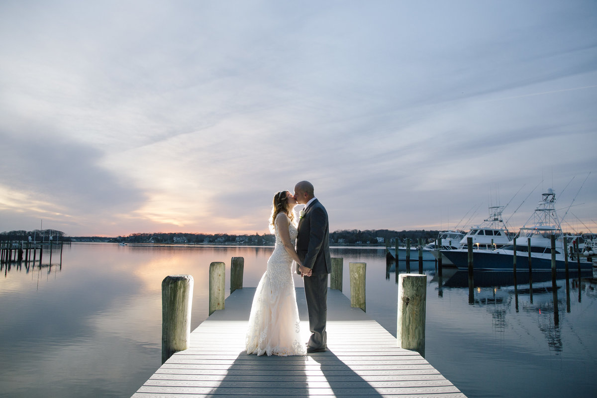 bride and groom kissing on dock at sunset at  clarks landing yacht club wedding