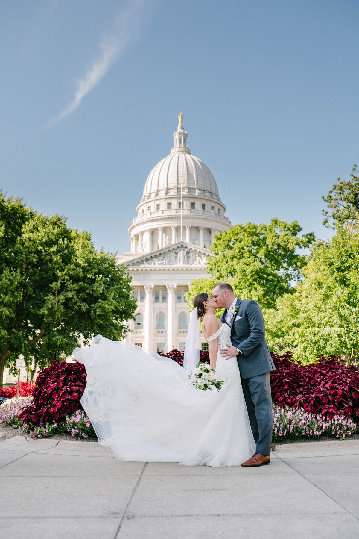 Bride and Groom kissing in front of Wisconsin State Capitol with dress flowing