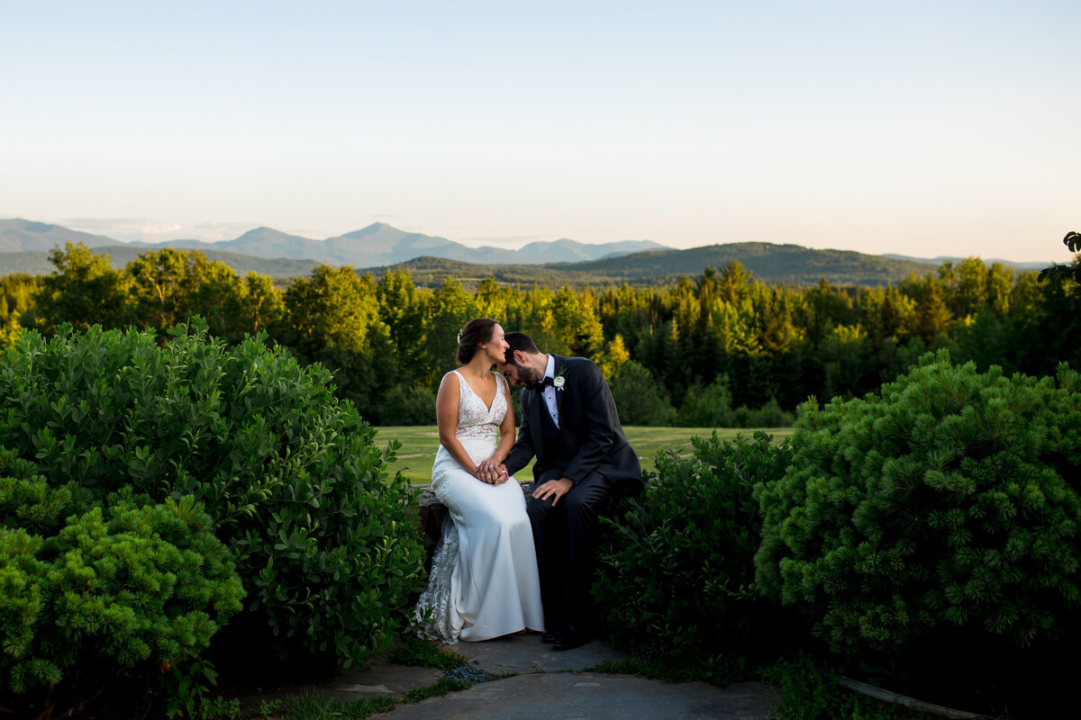 Tired couple relax into one another after their White Mountain NH wedding during golden hour