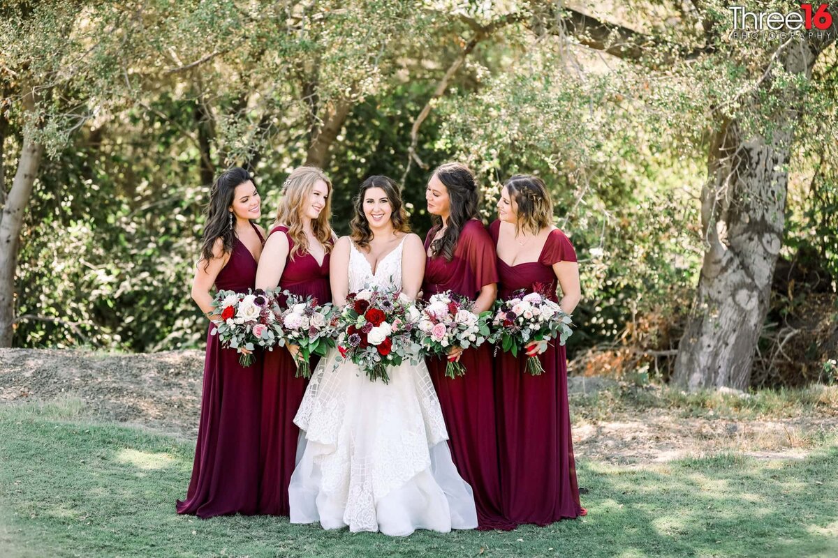 Maid of Honors surround the Bride as she smiles for the camera