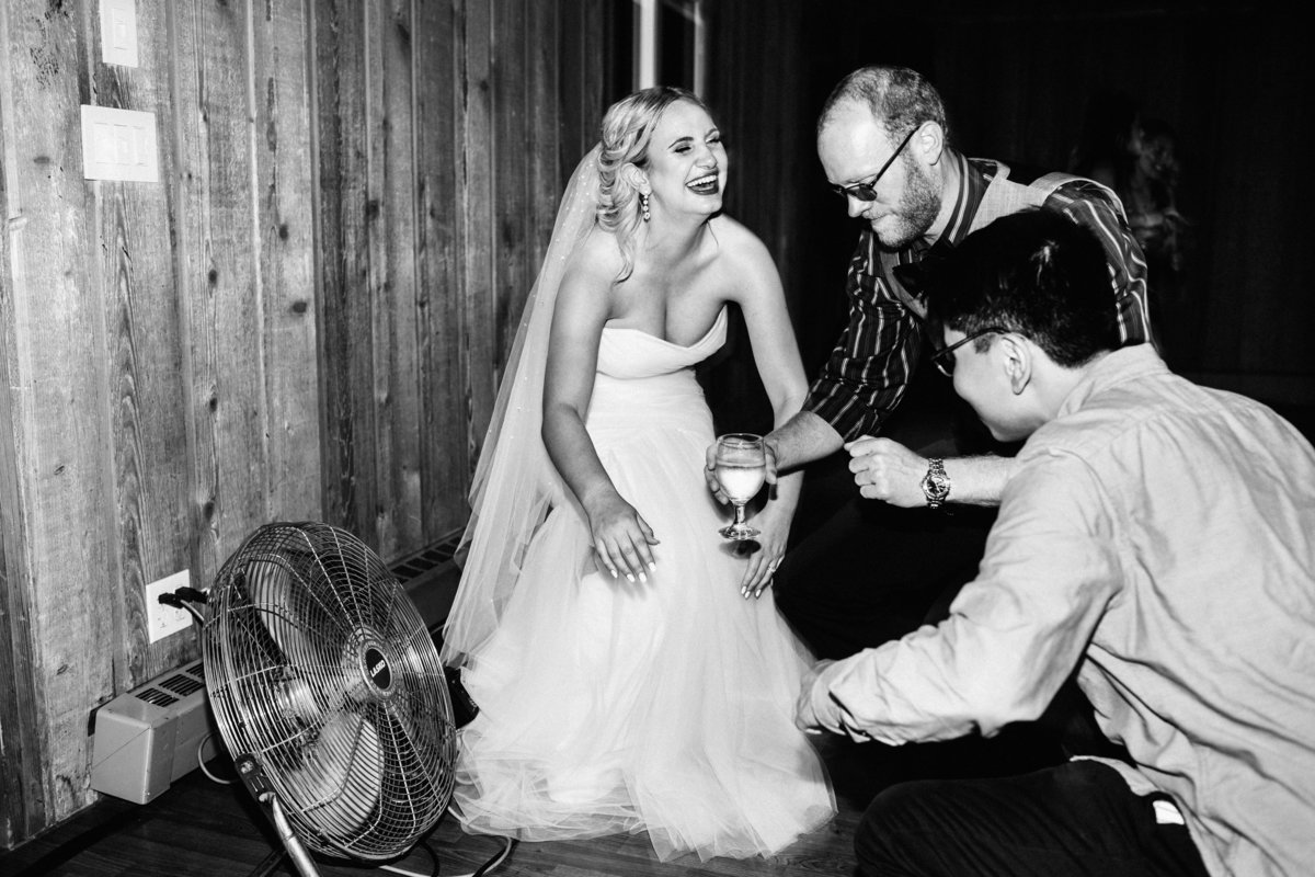 bride laughing while kneeling next to fan on the dance floor