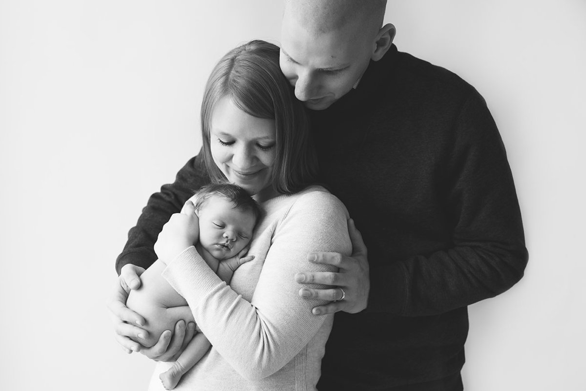 black and white image of parents holding their new baby in a studio