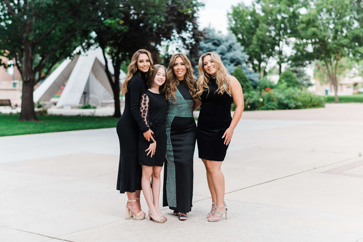 Northern Virginia family photographer takes an image of a beautiful mother and her three daughters while they stand together in complimenting black cocktail dresses