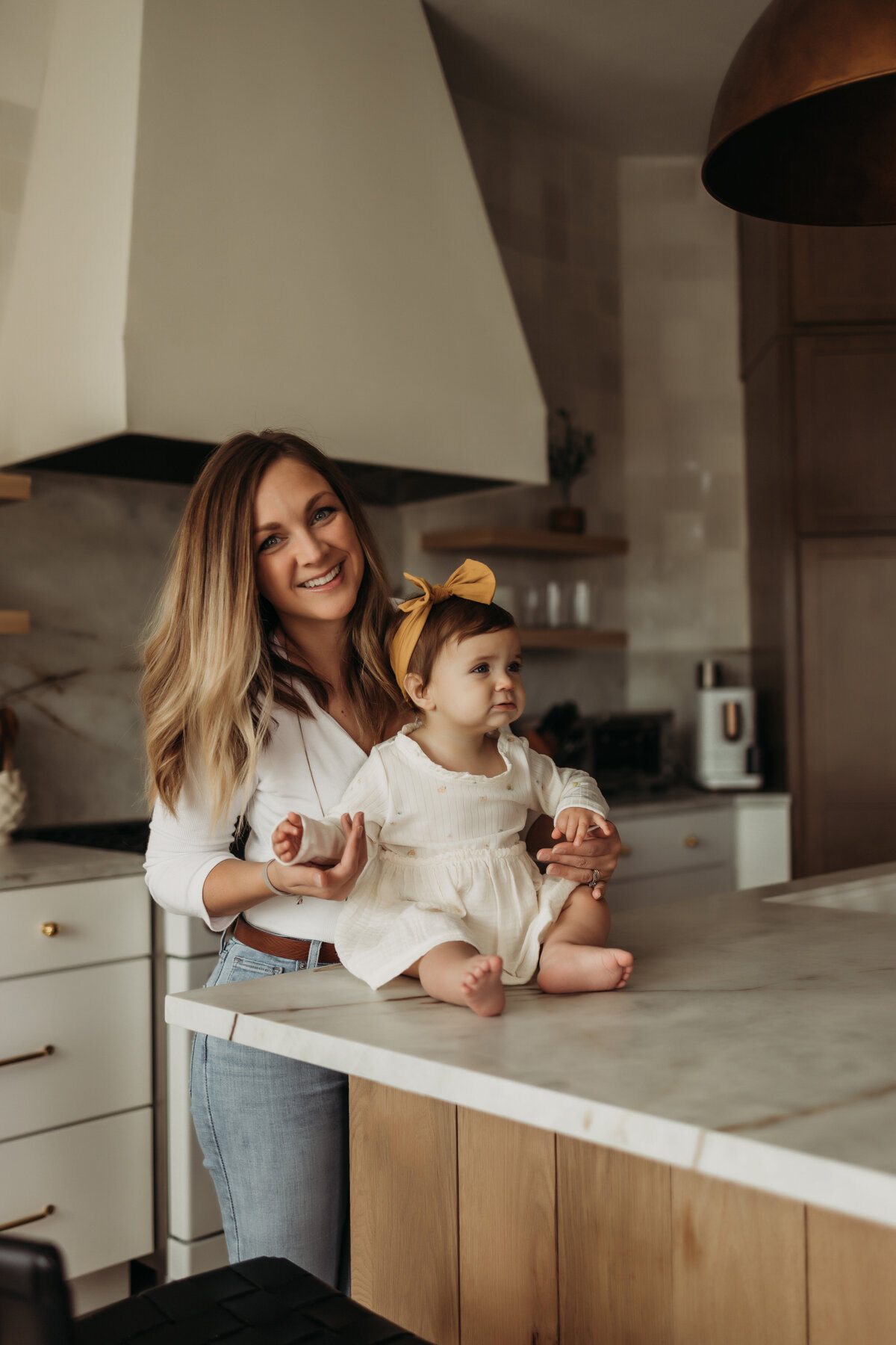mom holds young daughter on designer kitchen counter