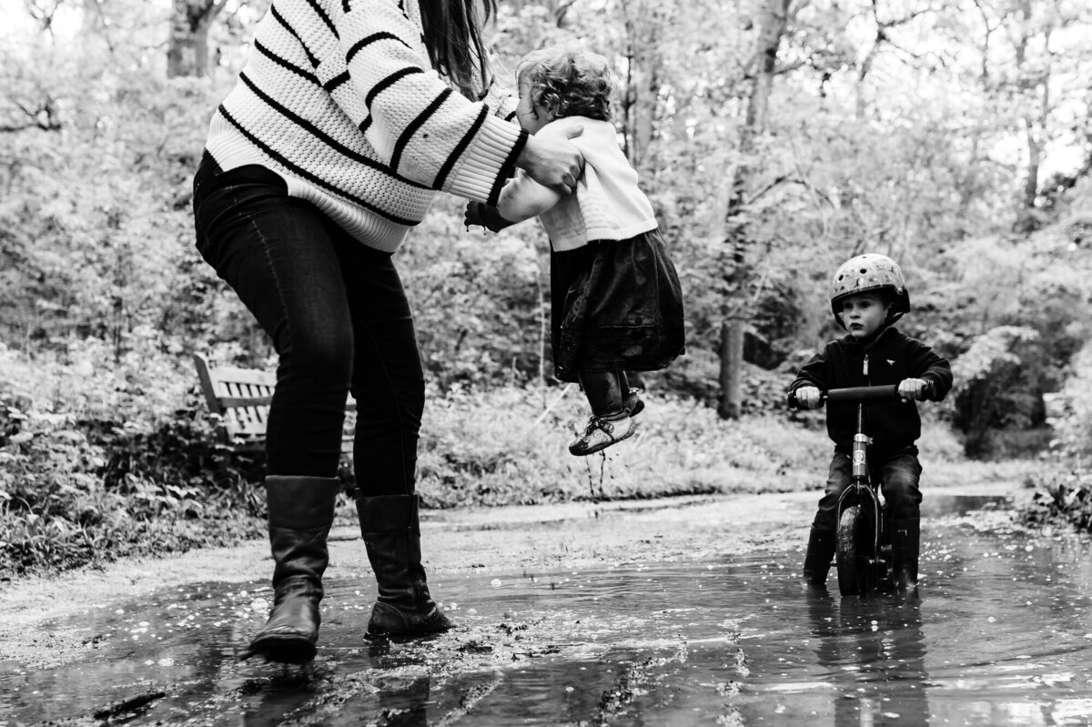 Little girl being picked up out of a puddle during family photoshoot at barnsdale woods