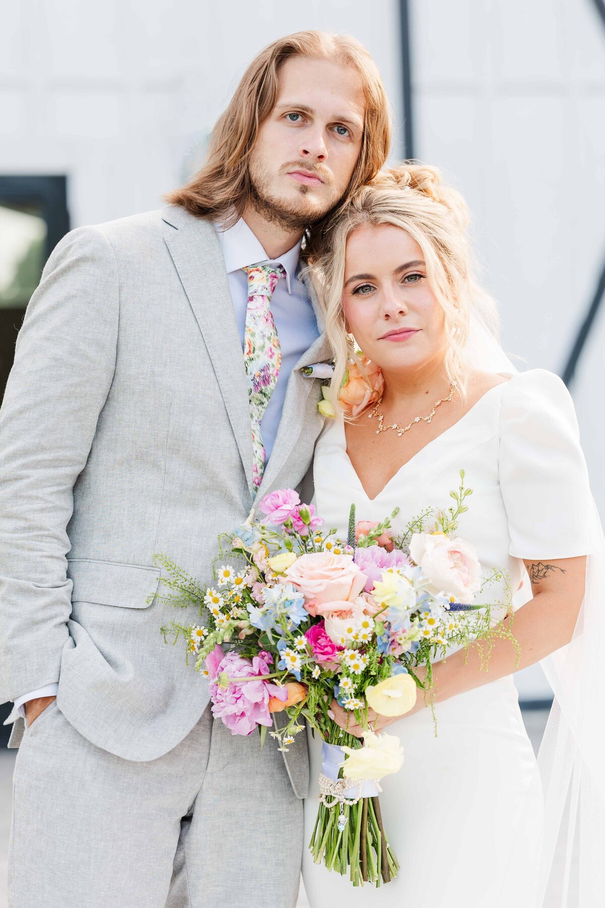 Bride and groom embracing each other and looking dramatically at the camera on their wedding day