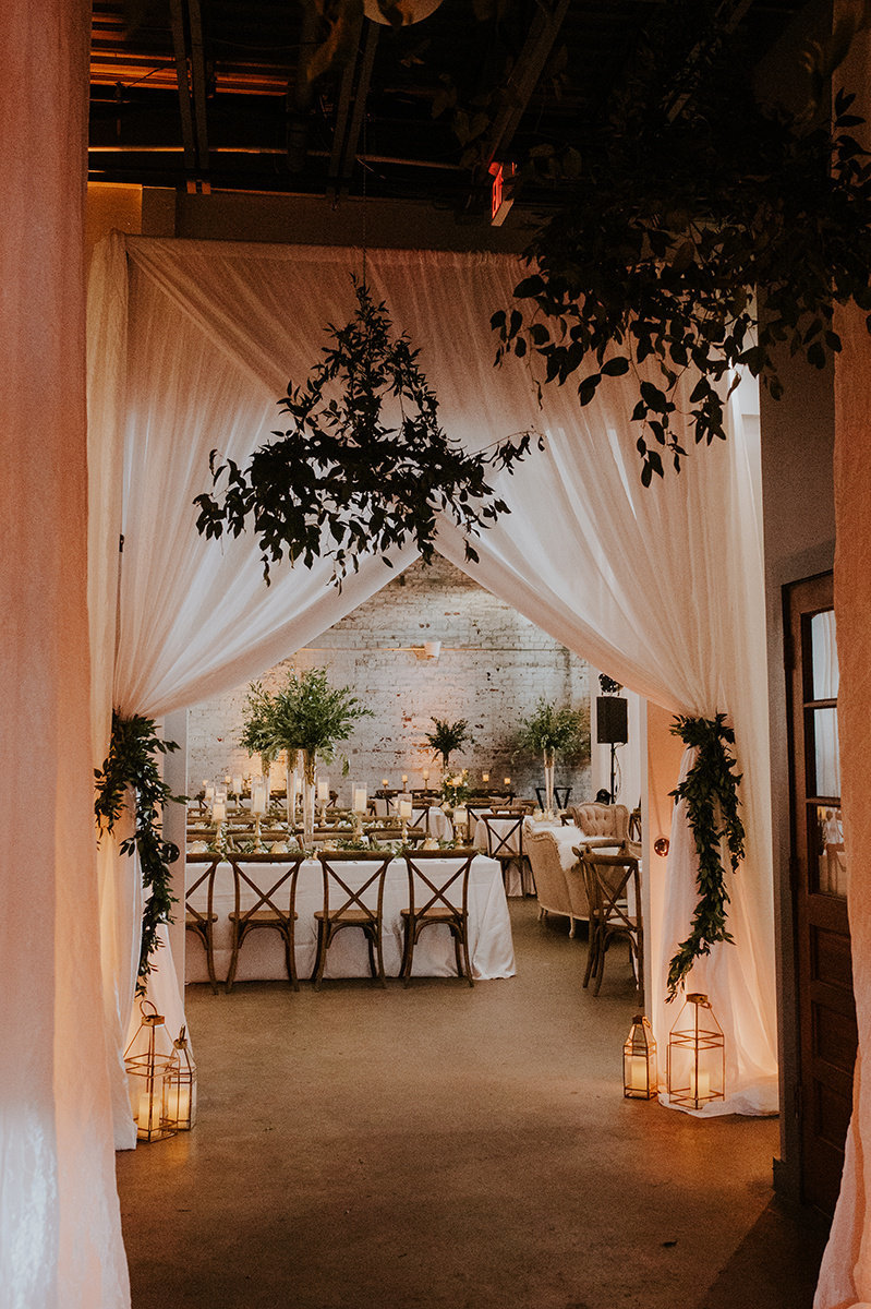 Greenery chandeliers with white draping into reception