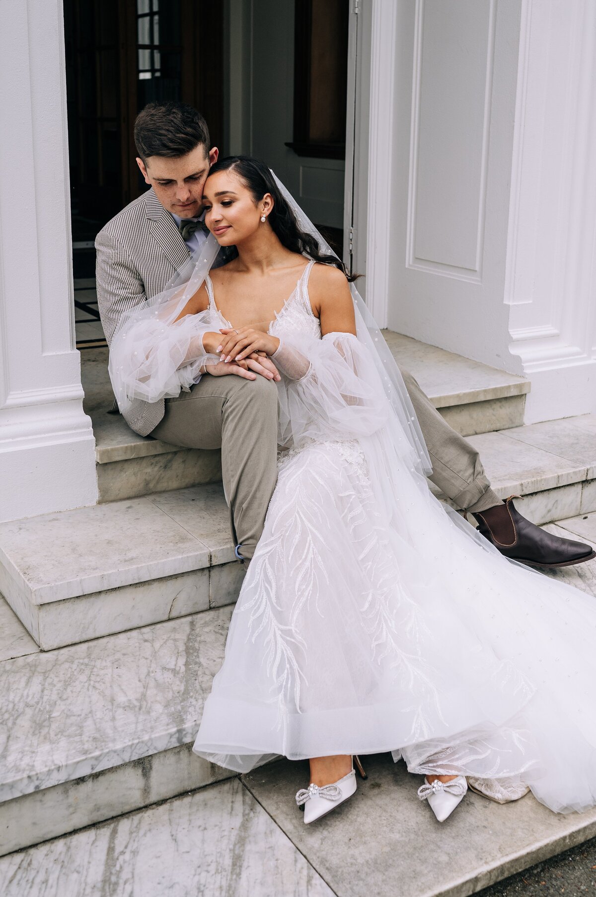 elegant wedding photo of couple sitting on white marble steps in invercargill new zealand