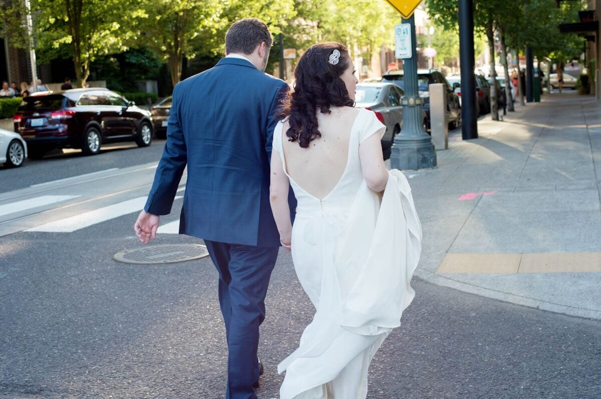 a bride and groom walk through downtown portland