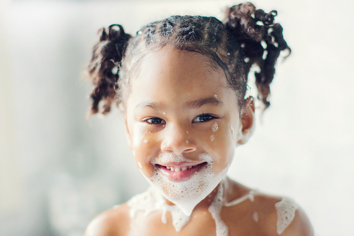 Girl has a soapy face from her bubble bath.