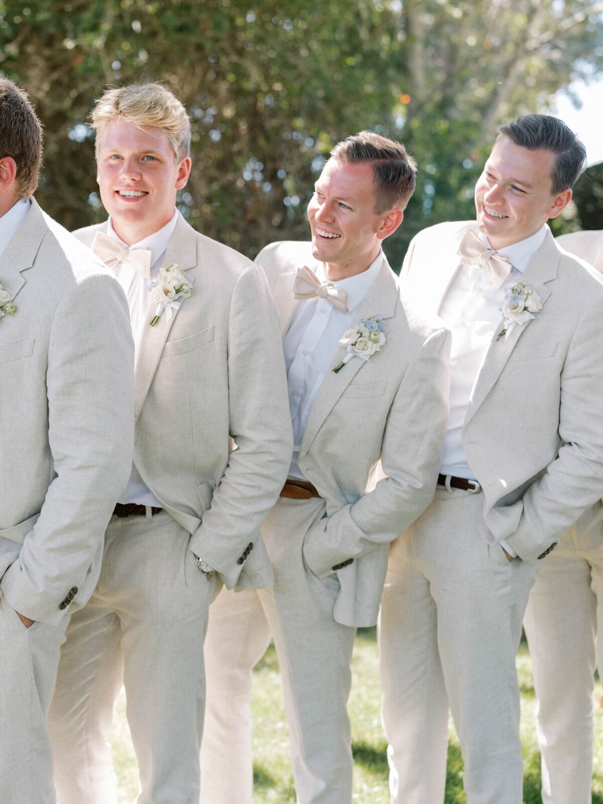 A line of groomsmen with white flower boutonnieres.