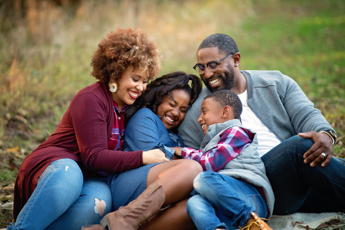 Family session located outside with family sitting on the ground