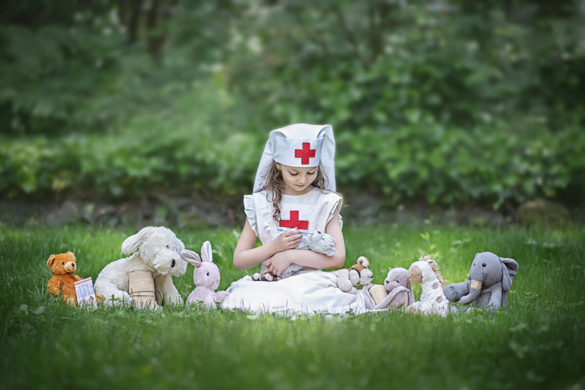 Little girl in nurse outfit treating sick stuffed animals
