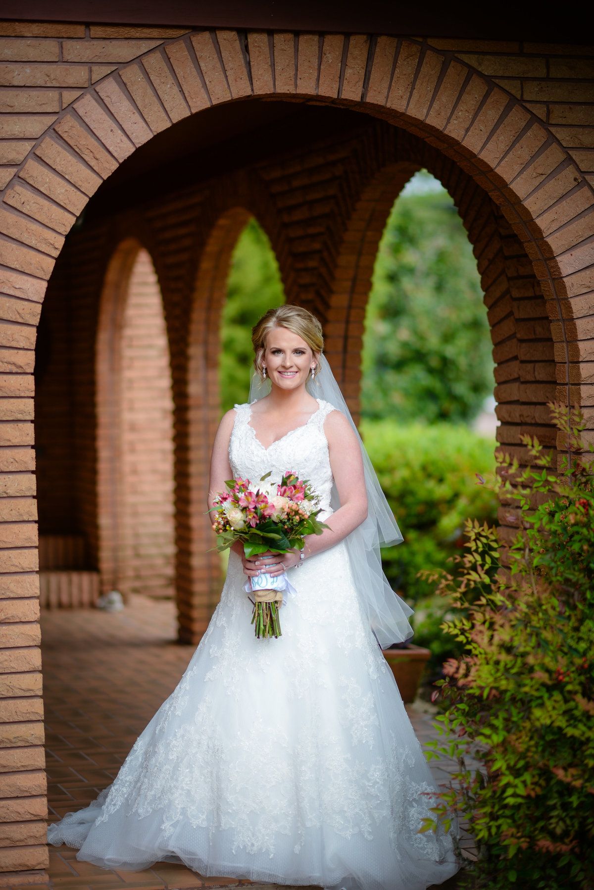 Beautiful bridal portrait photography: Bride with bouquet under a Spanish arch before her Mississippi wedding