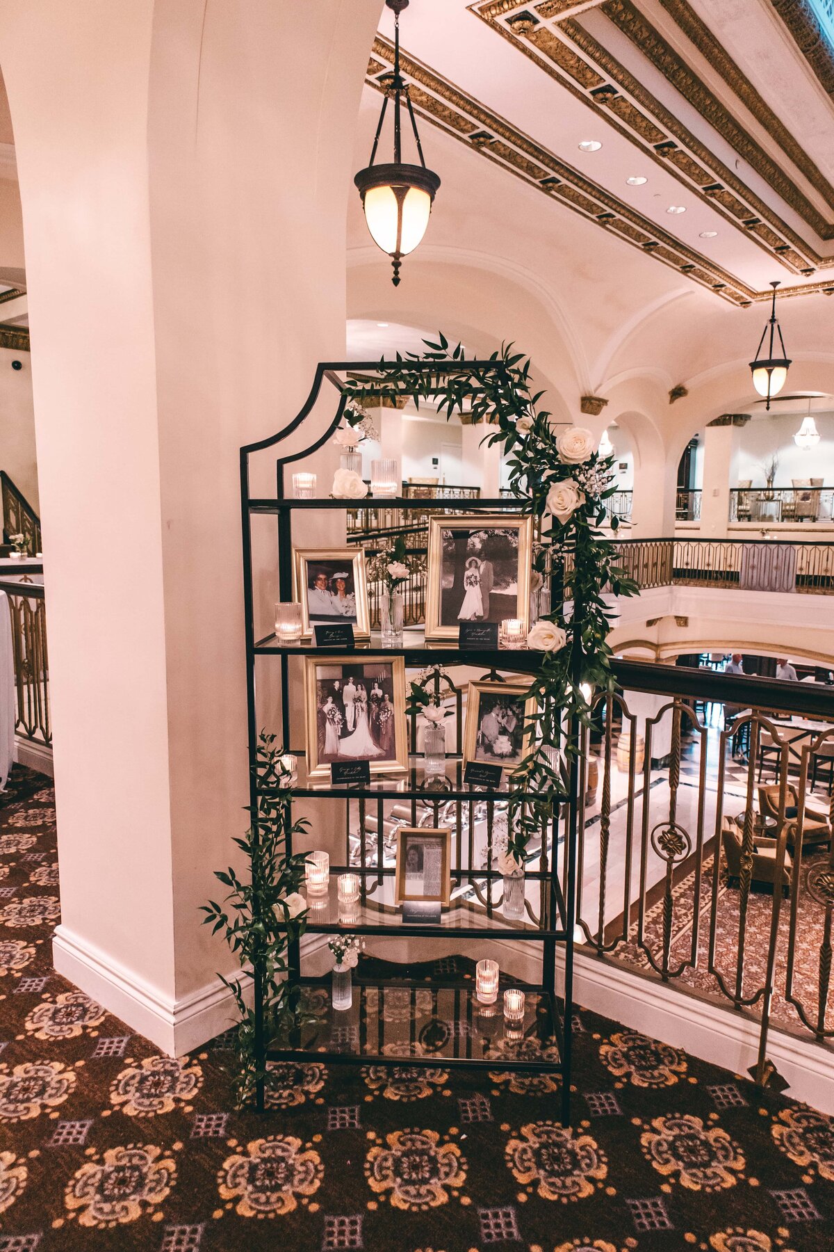 An elegantly decorated memorial with photos and candles on a metal stand in a hallway with arched ceilings and ornate light fixtures, perfect for events in Davenport.