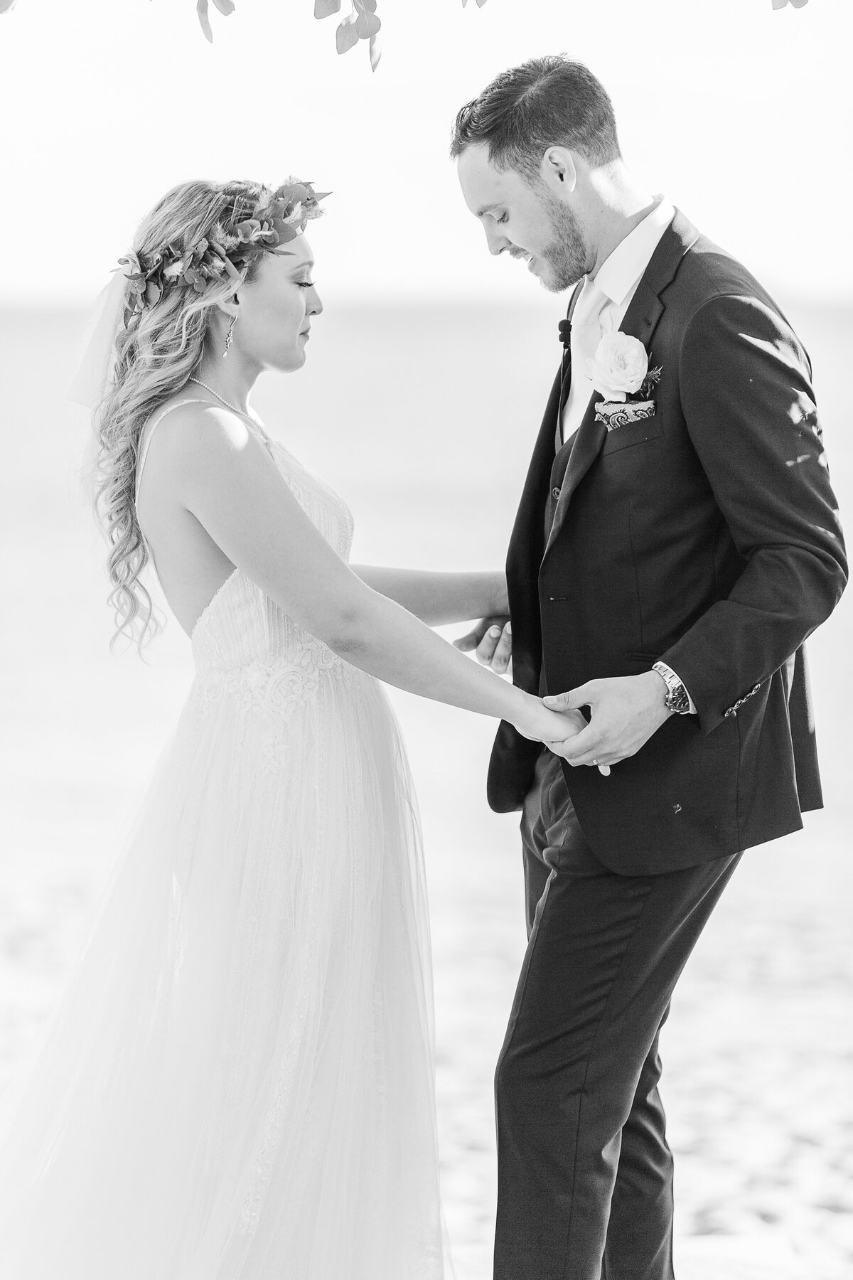Bride and groom hold hands and smile at each other on the beach at the Madison Beach Hotel. Captured by best New England wedding photographer Lia Rose Weddings.