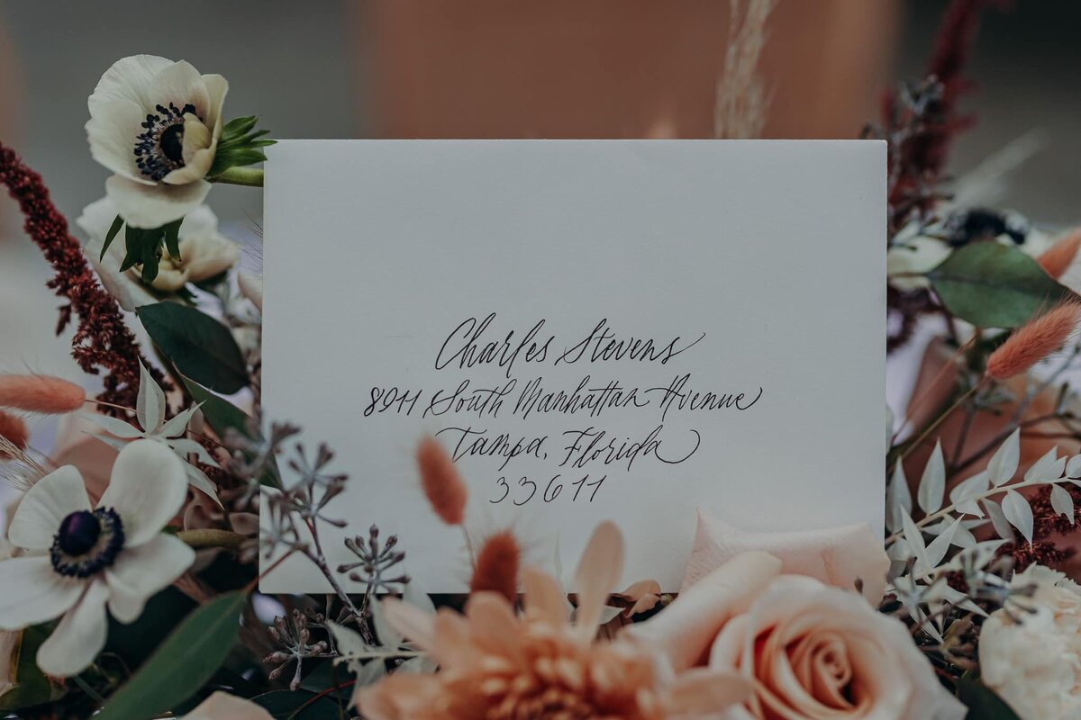 calligraphy envelope tucked into a wedding centerpiece