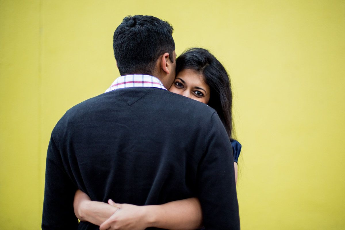 Indian fiancée looking over her fiancé's shoulder while on her engagement session with Expose The Heart Photography.