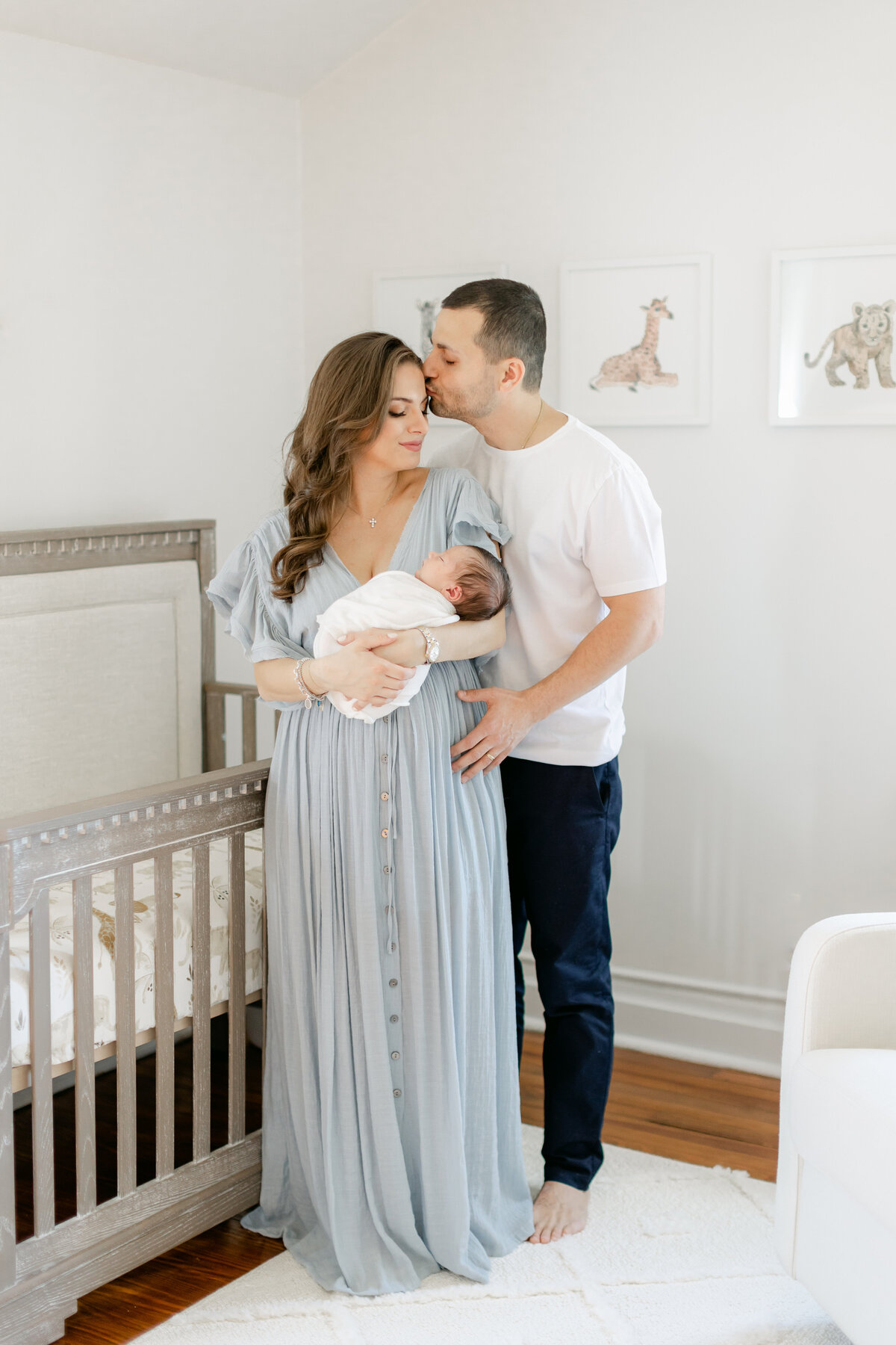 Mom and dad embrace in their baby's nursery during their newborn session photographed by Philadelphia Newborn Photographer Tara Federico