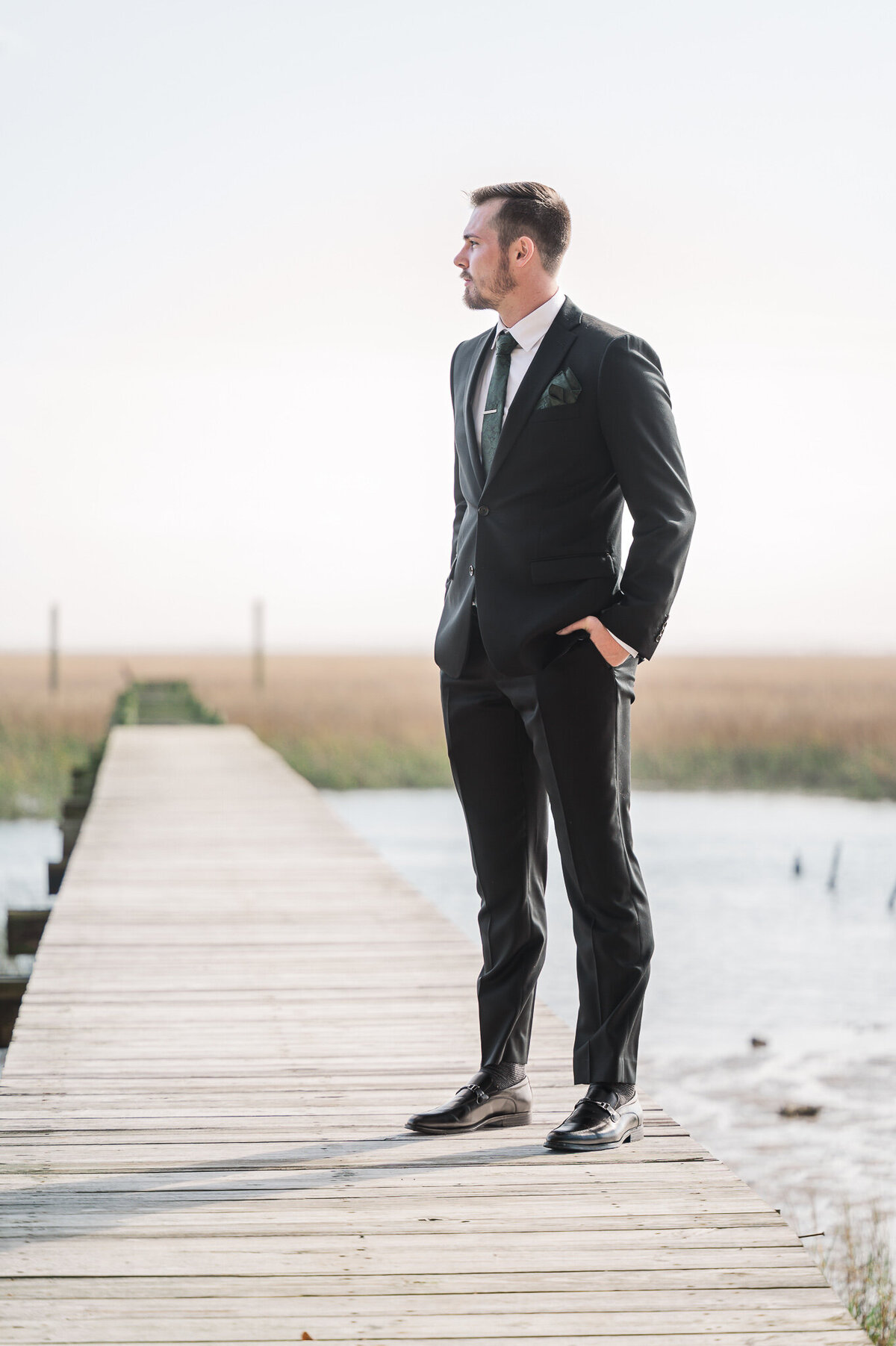 A groom overlooking the intracoastal waterways of Beaufort by JoLynn Photography, a North Carolina wedding photographer