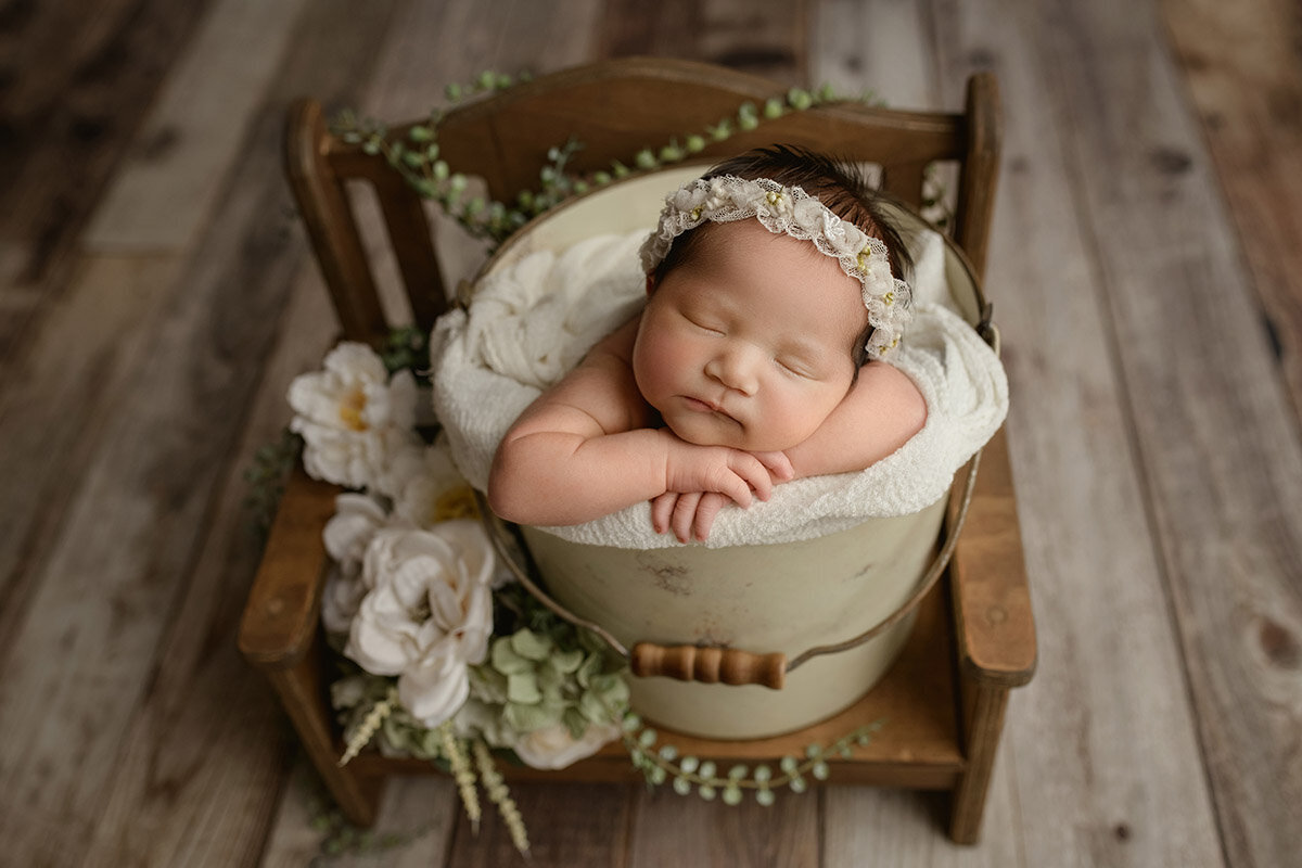 Newborn baby girl sleeping in a basket with flowers