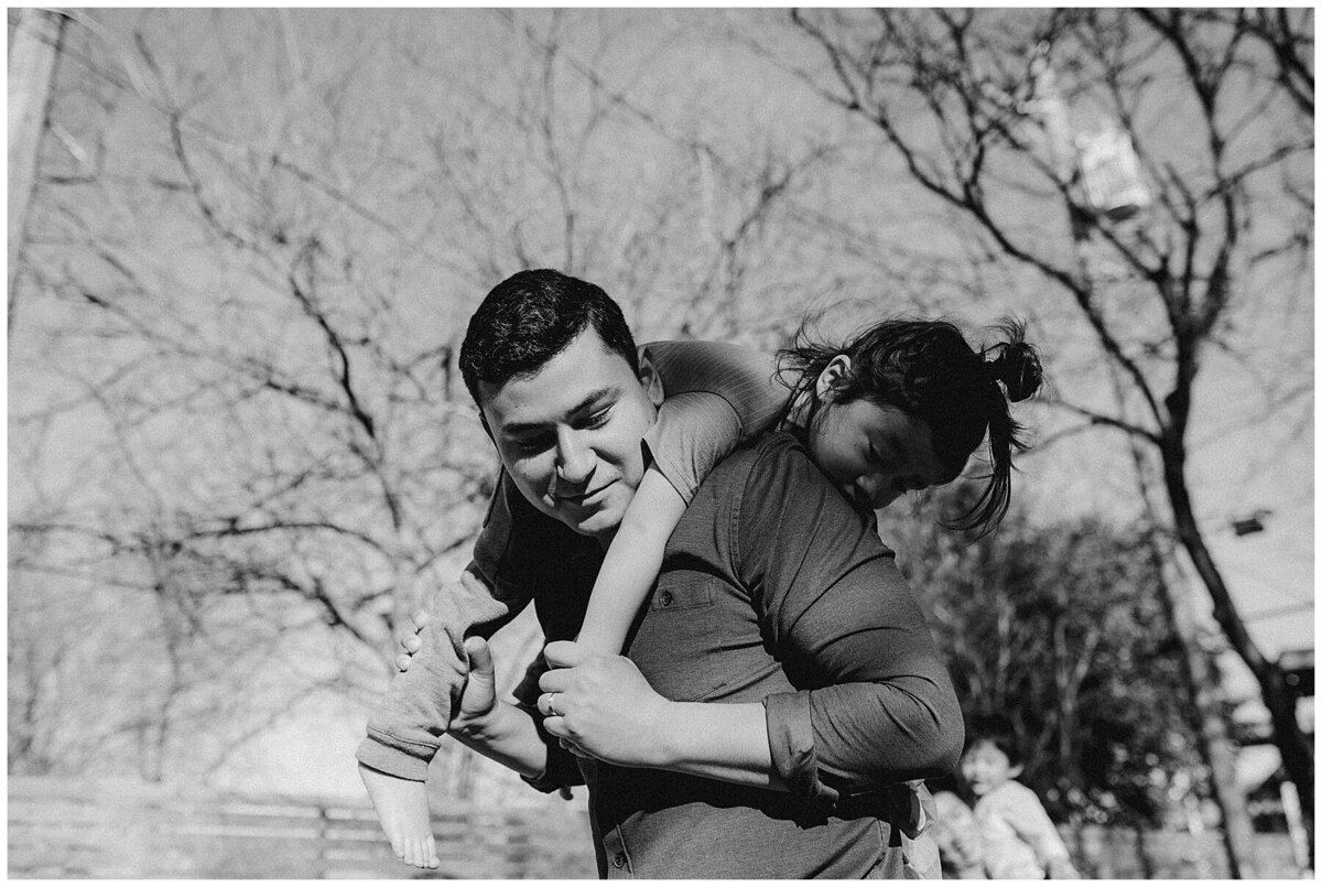 Father with child on his back at  garden family session in Austin by Amber Vickery Photography