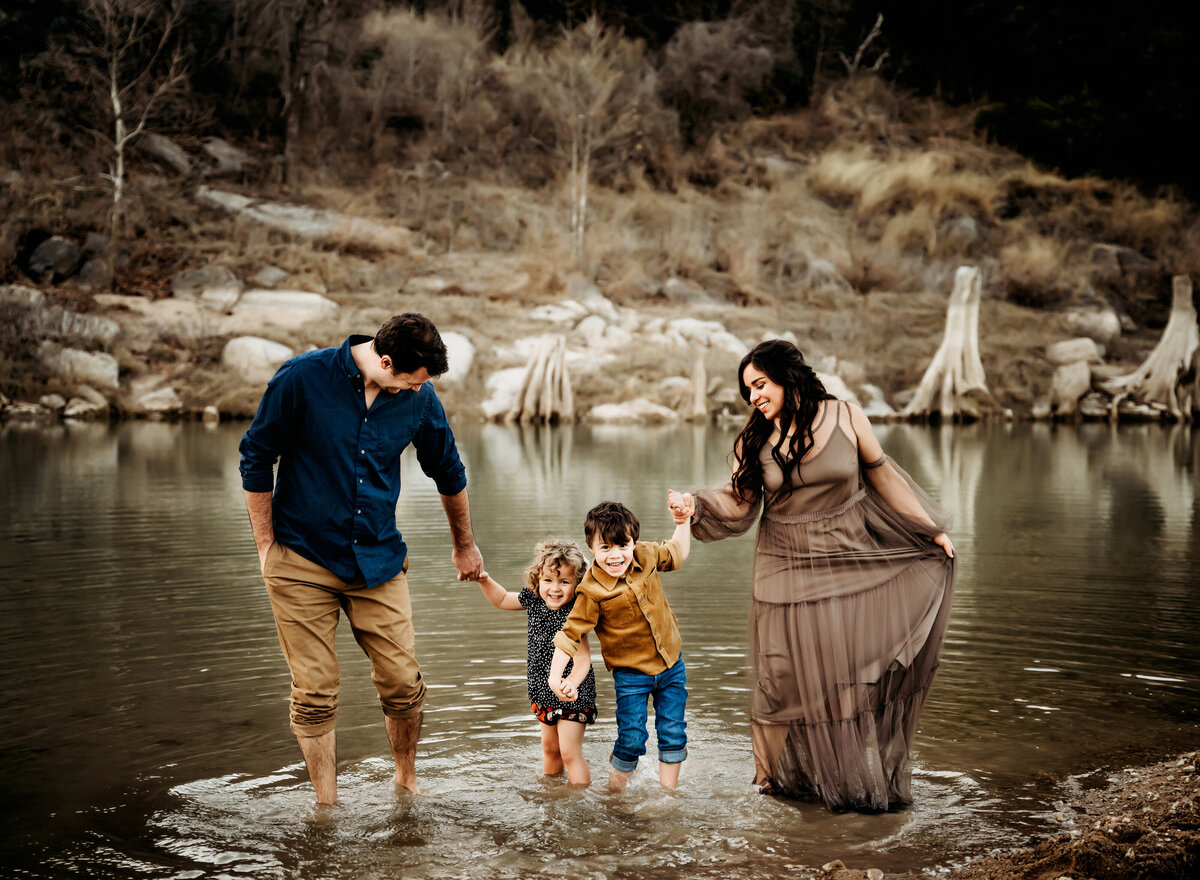 Family Photography, a mom and dad walk their small children hand-in-hand through a quiet still pond