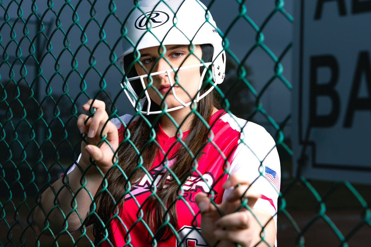 Softball senior athlete portrait in Lansing gym with moody lighting and creative sports photography.
