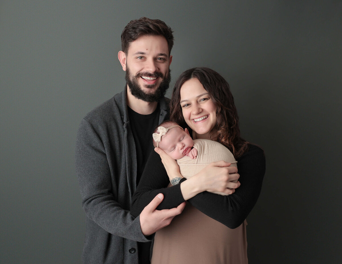Family posed with newborn daughter at our in-home Rochester, Ny studio.