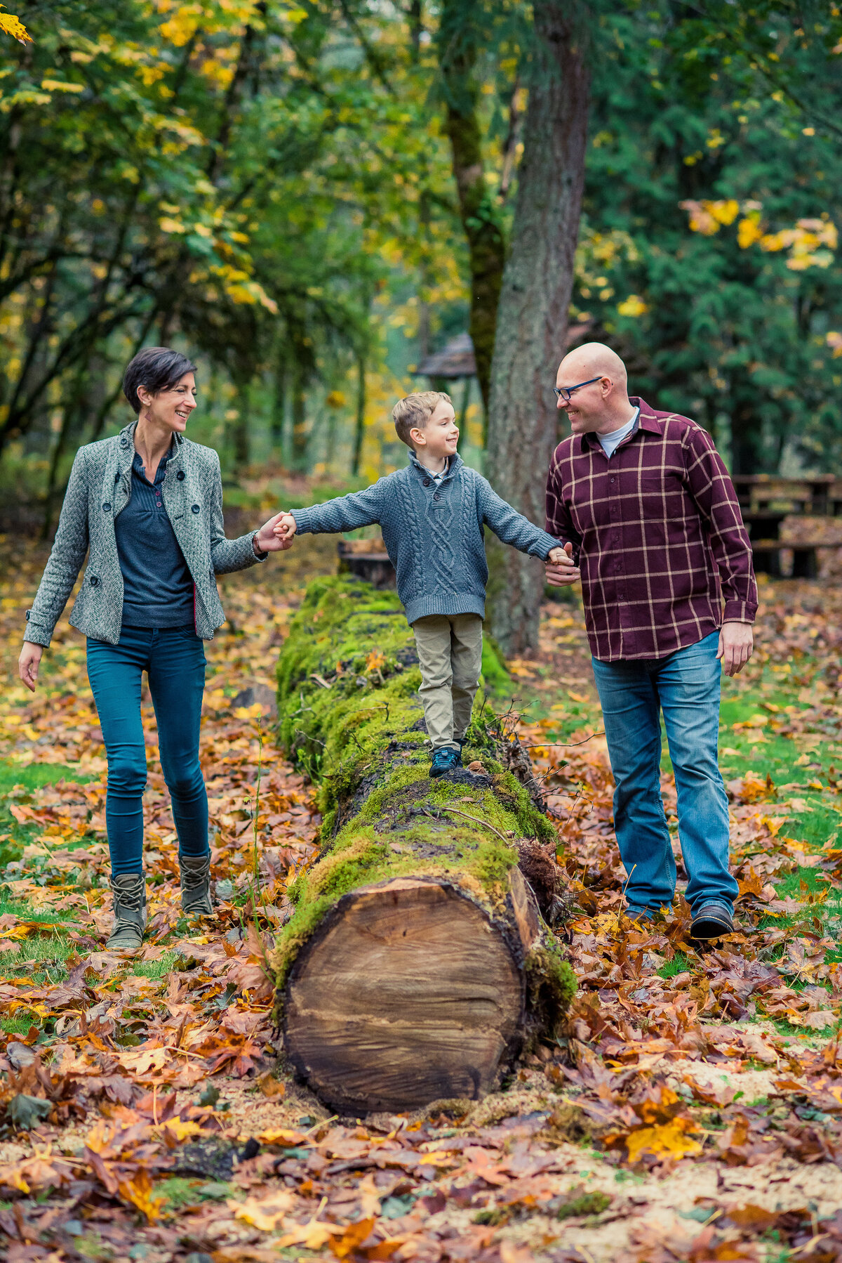 little boy walking on log with parents