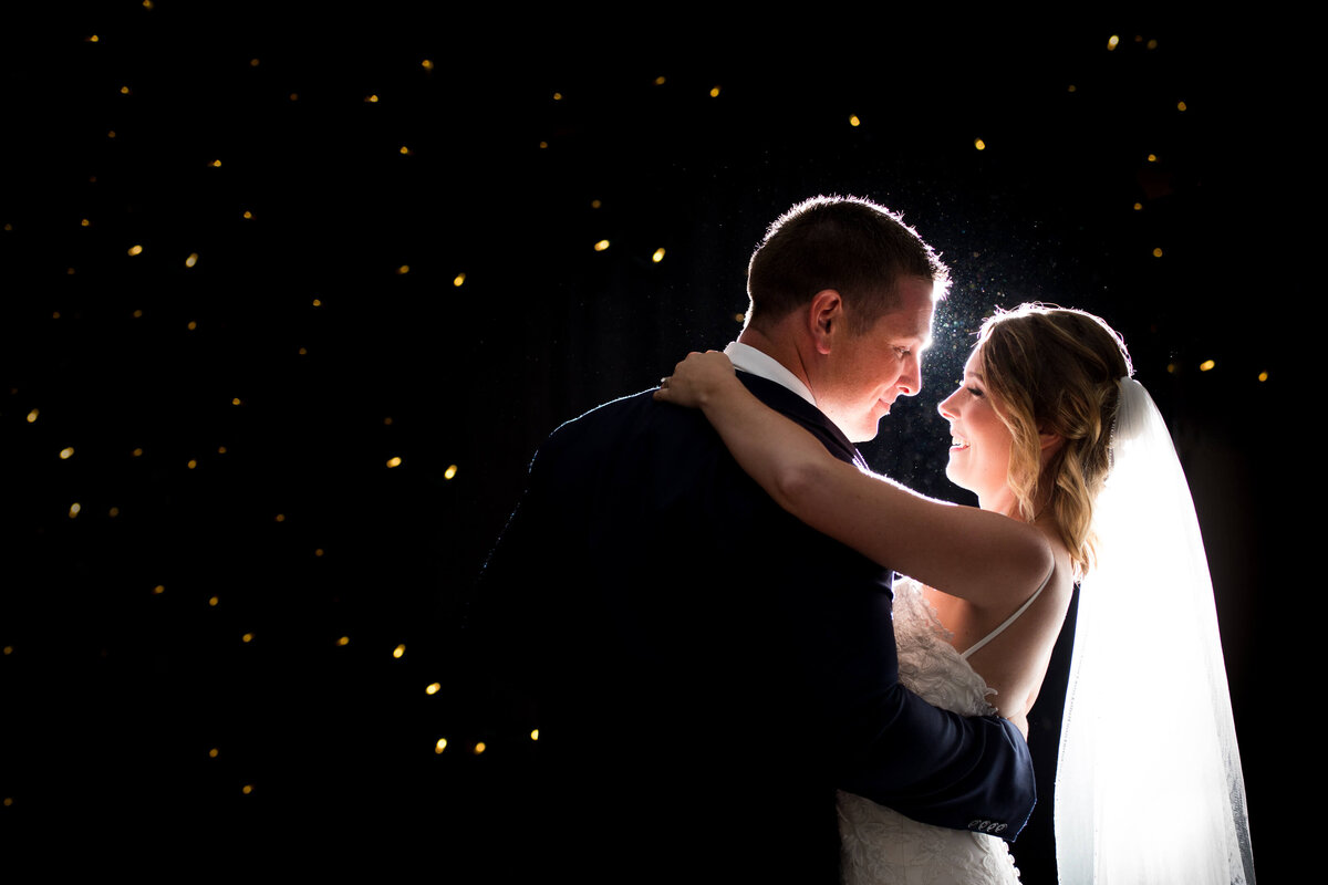 A bride and groom dance with twinkle lights in the background during their Ottawa wedding photos