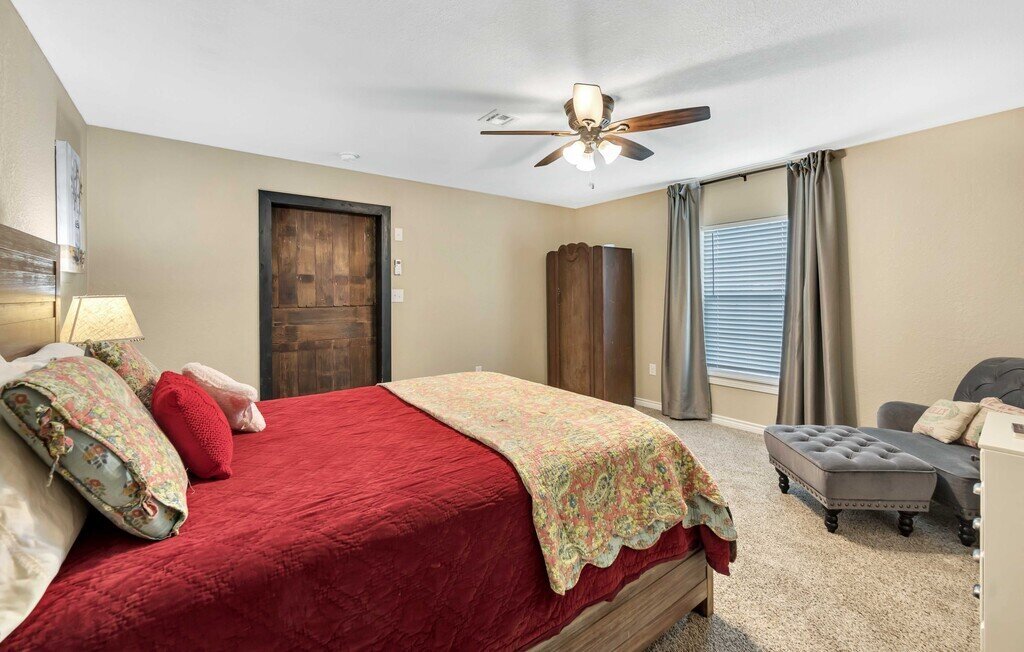 Bedroom with comfortable bedding in this four-bedroom, four-bathroom vacation rental home and guest house with free WiFi, fully equipped kitchen, firepit and room for 10 in Waco, TX.