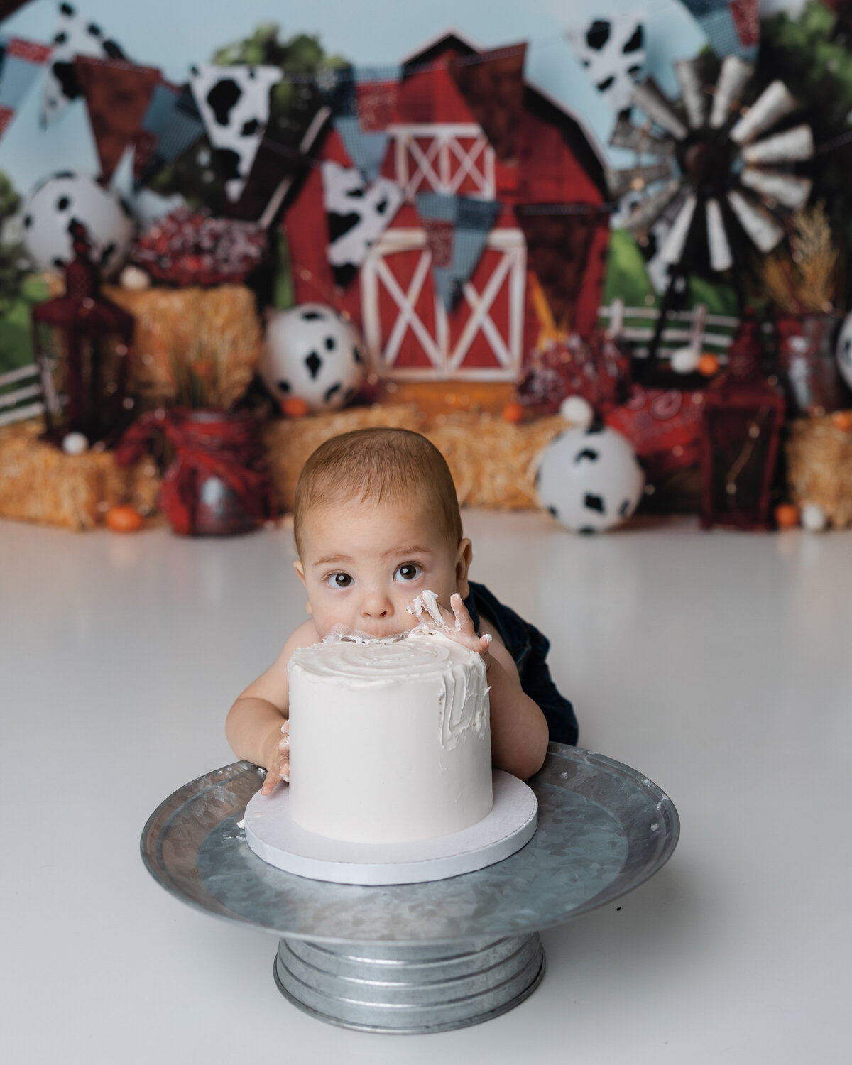 Adorable little one enjoying their cake smash moment in a farm-themed setting, blissfully tasting the frosting. Captured by Yucaipa cake smash photographer Kaitlyn Dawn Photography.