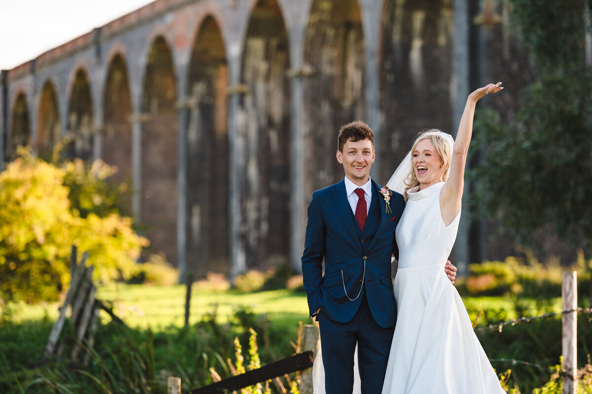 Bride and groom posing near harringworth viaduct
