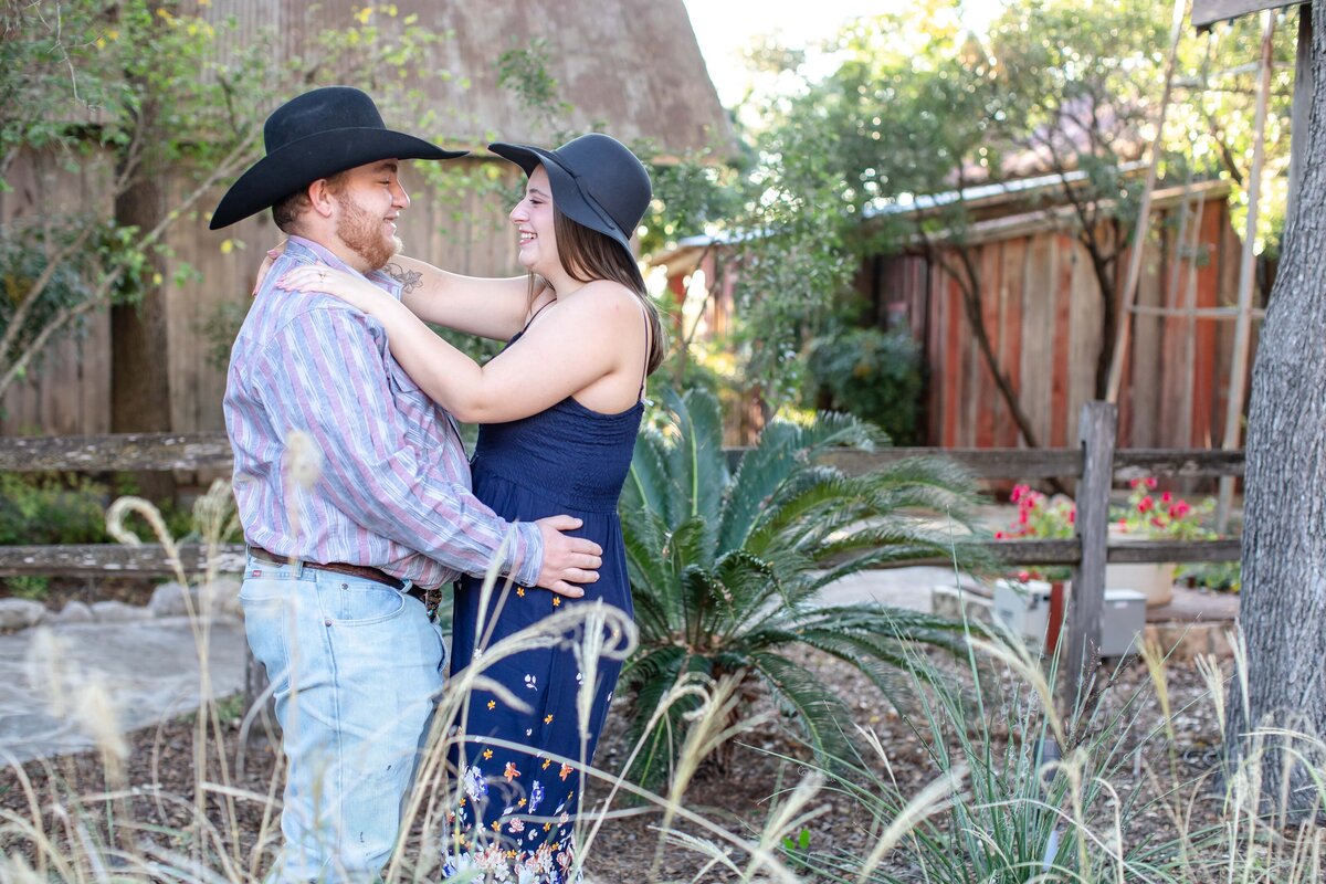 floppy hat in Gruene Texas  wedding engagement  with red barn and blue dress