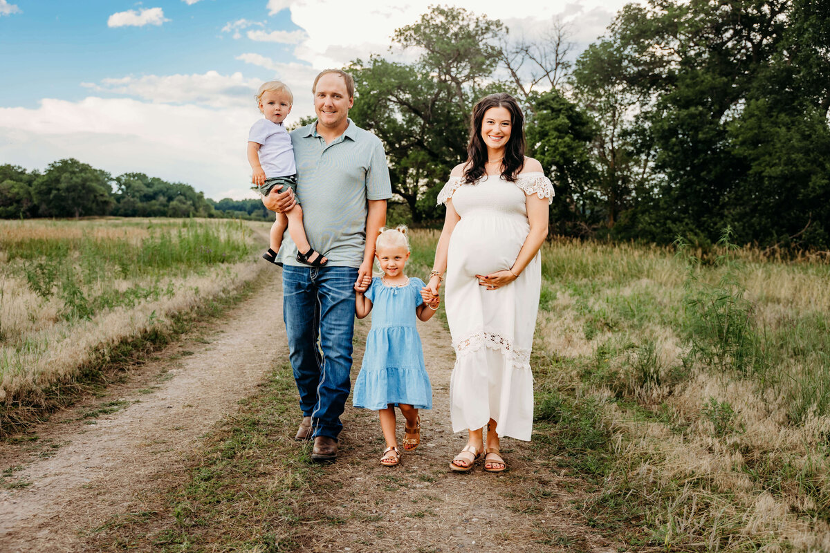 Family with 2 small children are walking down an untraveled road.