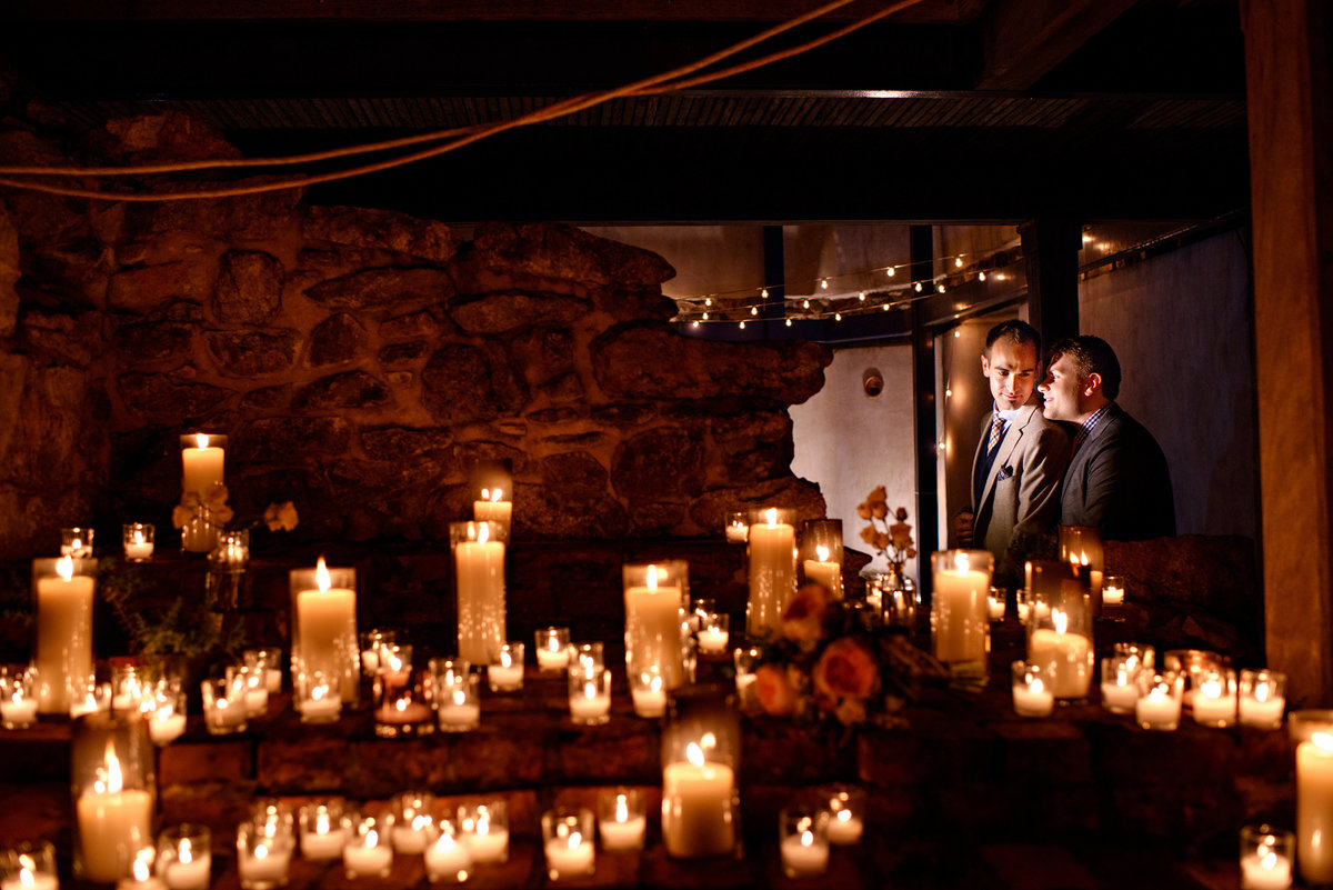 A gay wedding couple surrounded by candles at their same sex wedding.