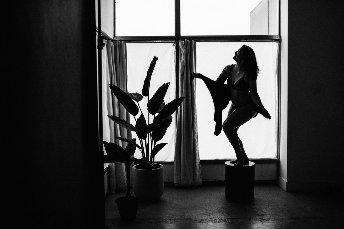 wide shot of silhouetted woman and large houseplant
