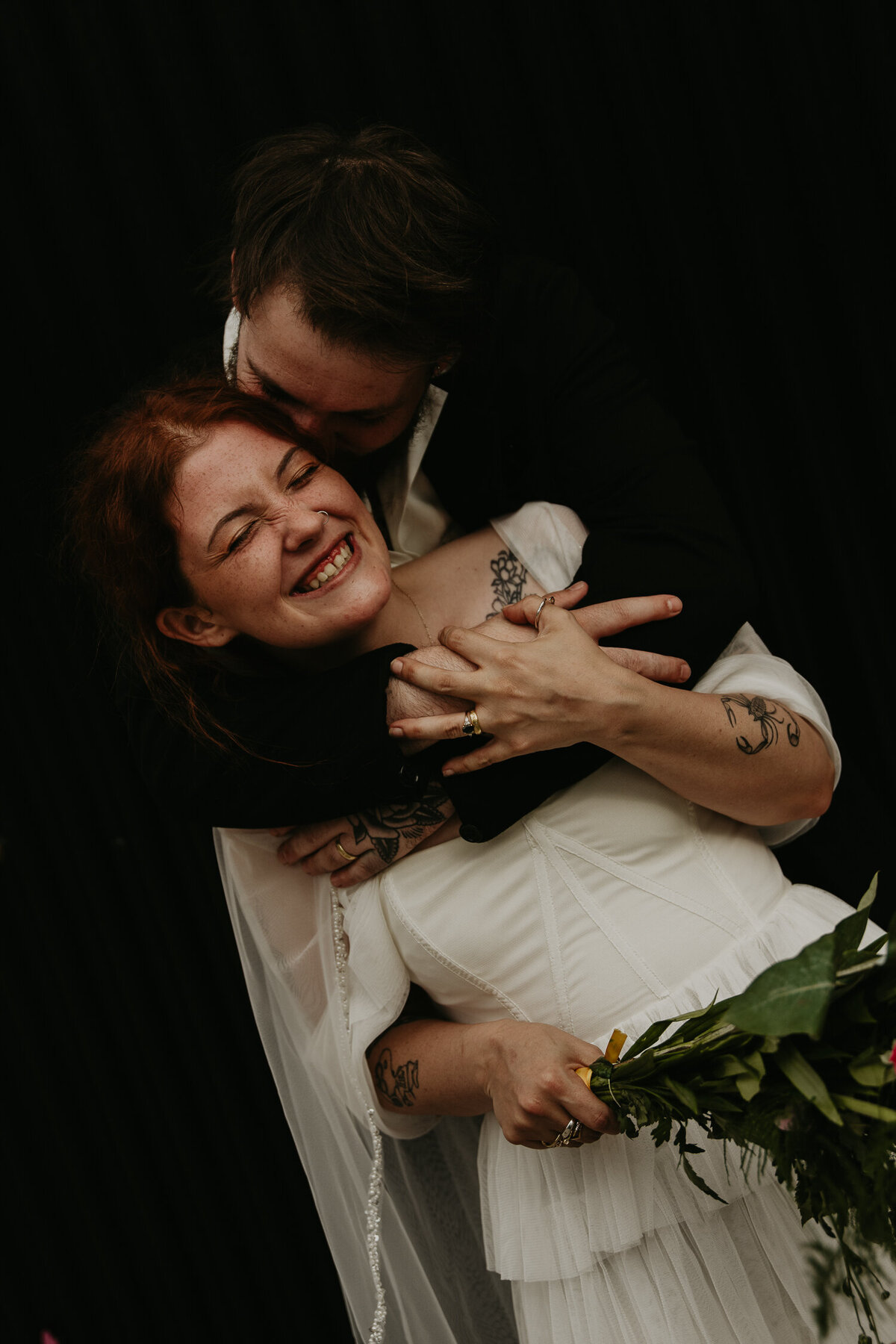 A groom hugs his bride from behind during their wedding photos at The Shack Revolution. 