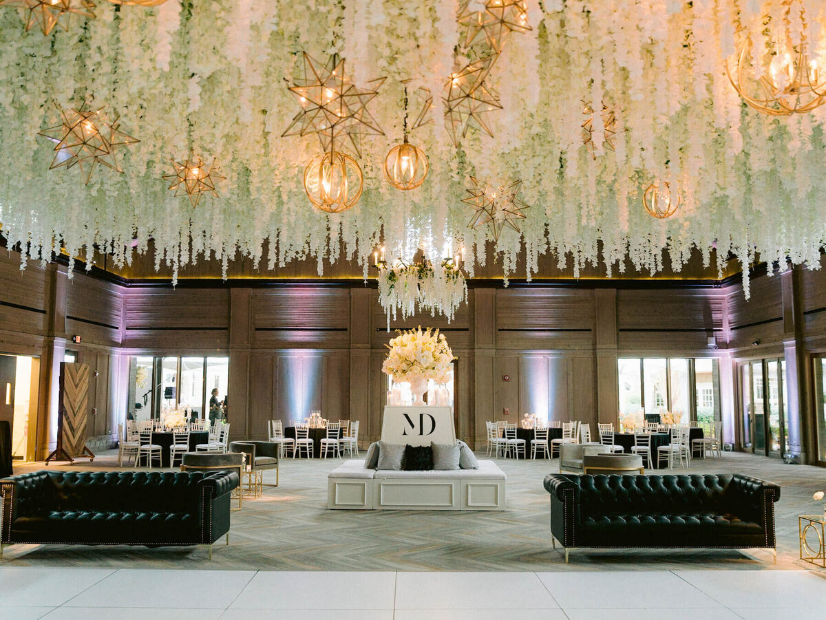 White dance floor with black sofas and gold star chandeliers