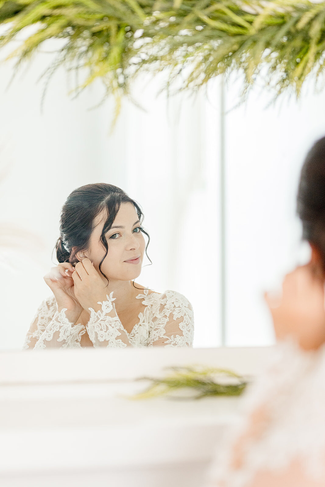 bride putting her earrings on looking in the mirror